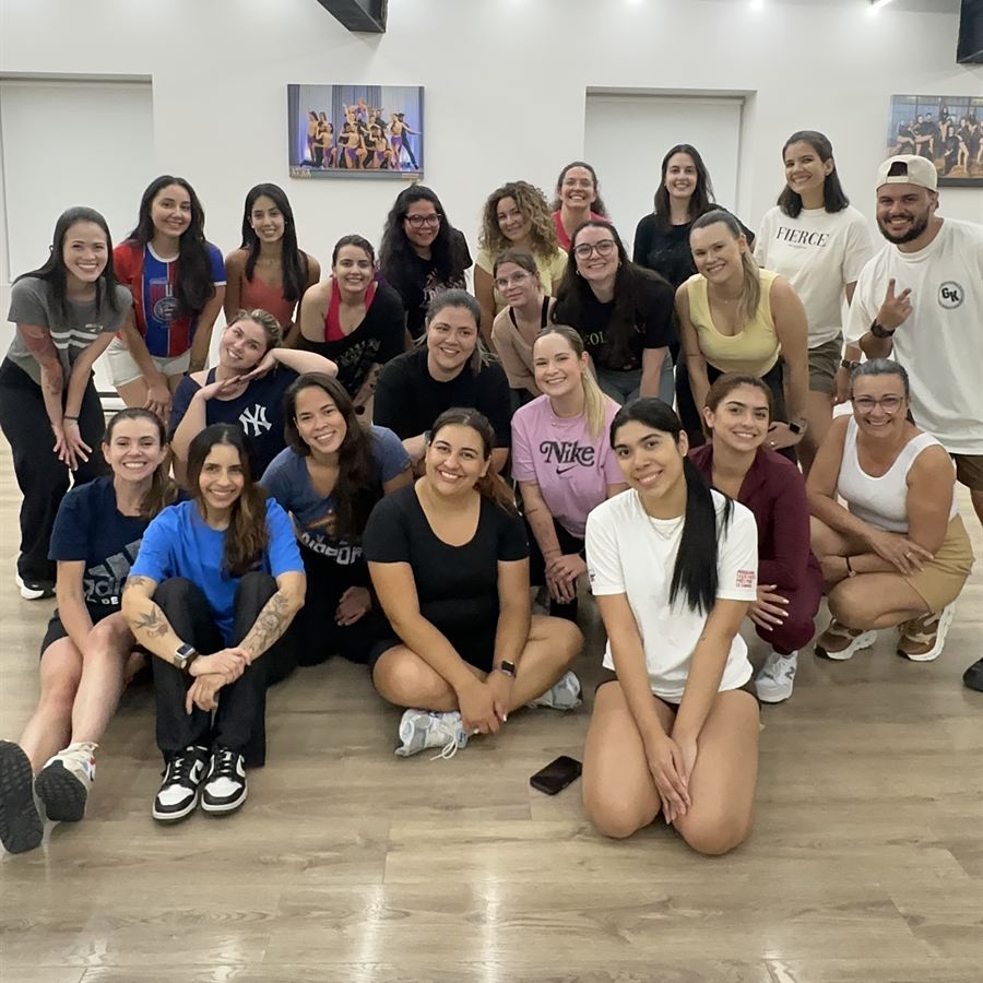 Smiling Brasileirada students sitting and crouching together after a dance class