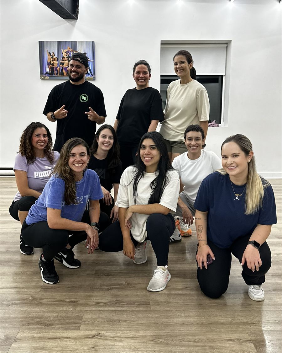 Brasileirada students of different ages and styles crouching together and smiling after class